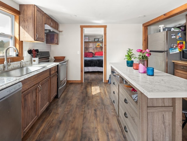 kitchen featuring sink, dark hardwood / wood-style floors, appliances with stainless steel finishes, tasteful backsplash, and a kitchen island