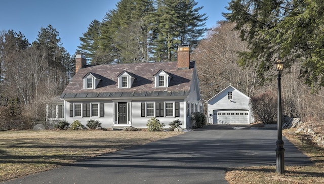 cape cod home featuring an outbuilding and a garage