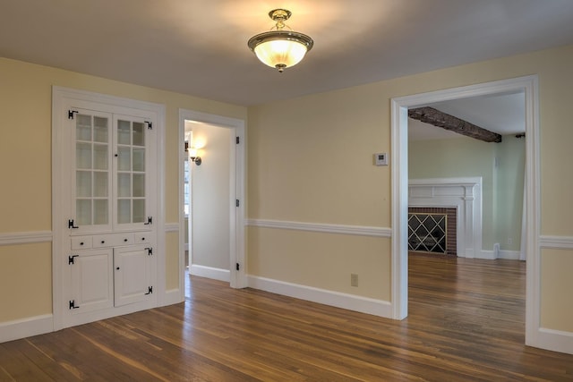 unfurnished room featuring dark wood-type flooring and a brick fireplace