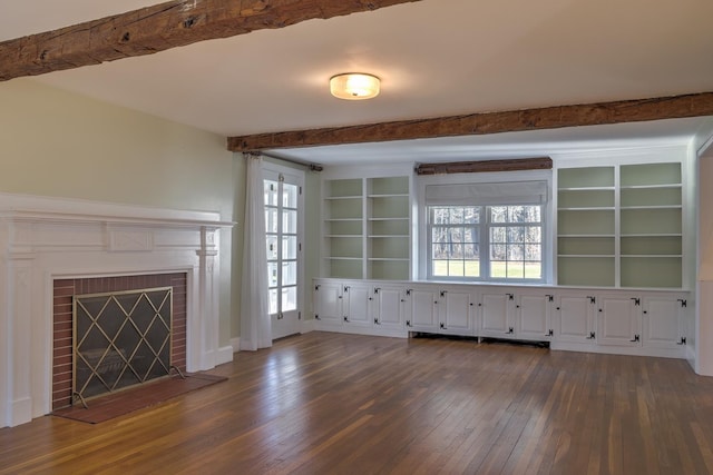 unfurnished living room featuring a fireplace, beam ceiling, a wealth of natural light, and dark wood-type flooring