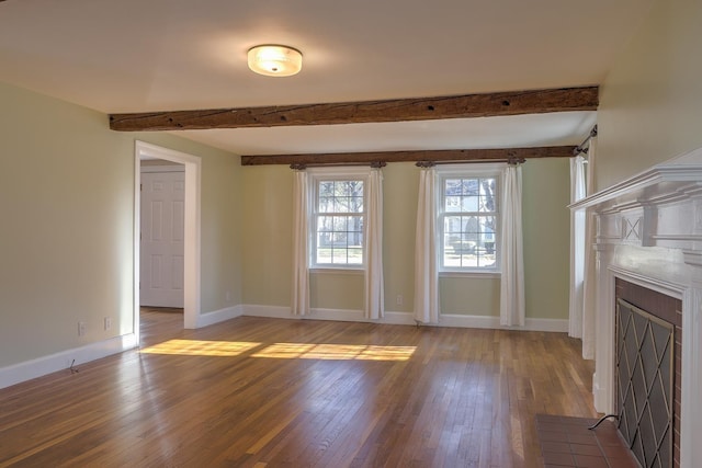 unfurnished living room with beam ceiling, a tile fireplace, and wood-type flooring