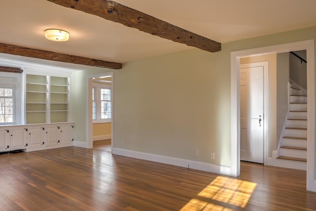 spare room featuring dark hardwood / wood-style floors, beam ceiling, and a wealth of natural light