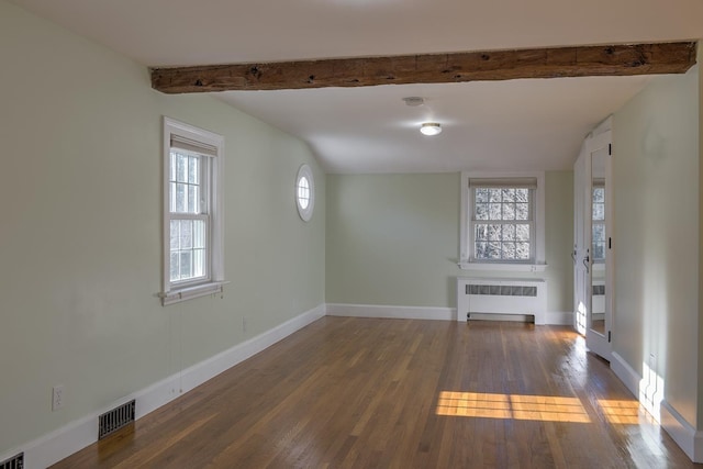 unfurnished living room featuring beamed ceiling, dark wood-type flooring, and radiator