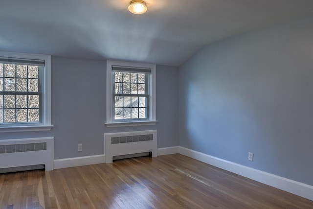 spare room with hardwood / wood-style flooring, lofted ceiling, and radiator heating unit