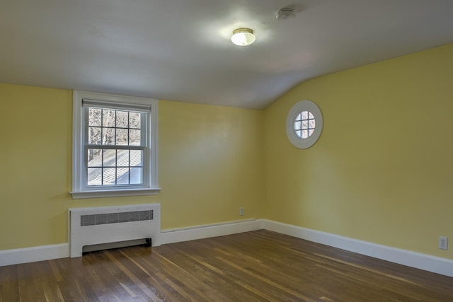 spare room with lofted ceiling, radiator heating unit, and dark wood-type flooring