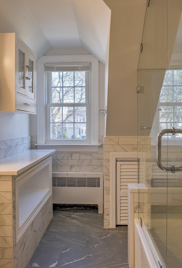 bathroom featuring radiator heating unit, vaulted ceiling, and plenty of natural light