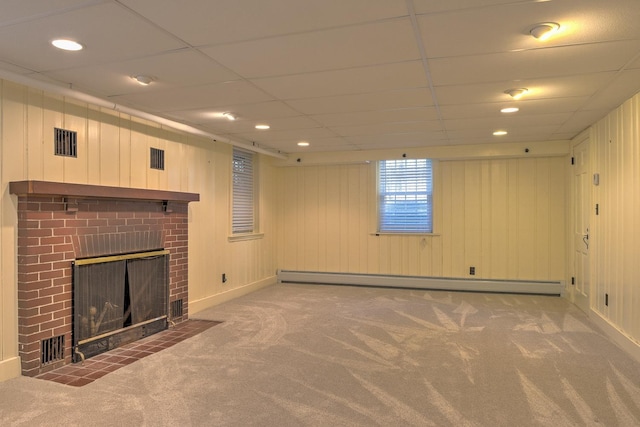 basement with baseboard heating, a paneled ceiling, carpet flooring, and a brick fireplace