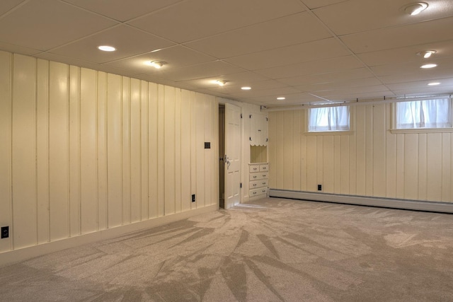 basement featuring carpet flooring, wood walls, and a baseboard heating unit