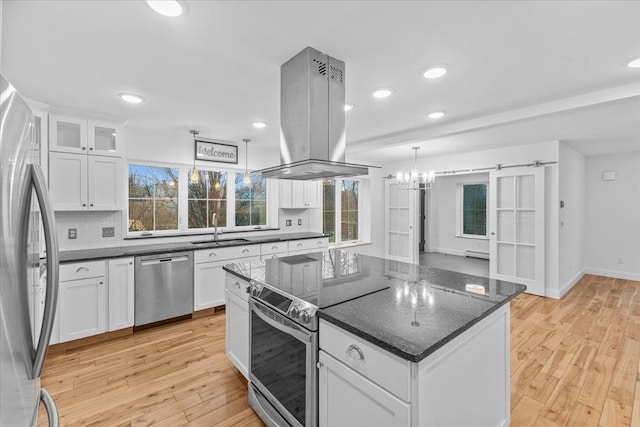 kitchen featuring pendant lighting, island range hood, white cabinetry, and appliances with stainless steel finishes