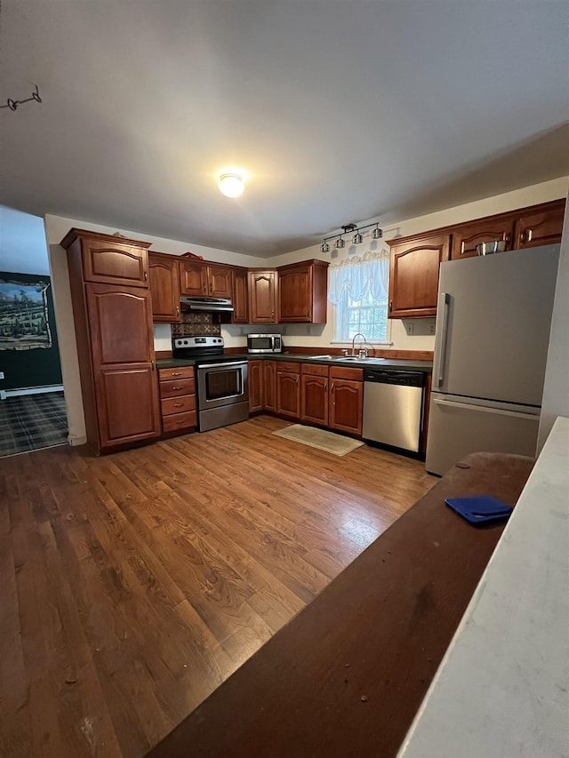 kitchen with stainless steel appliances, track lighting, dark hardwood / wood-style floors, and sink