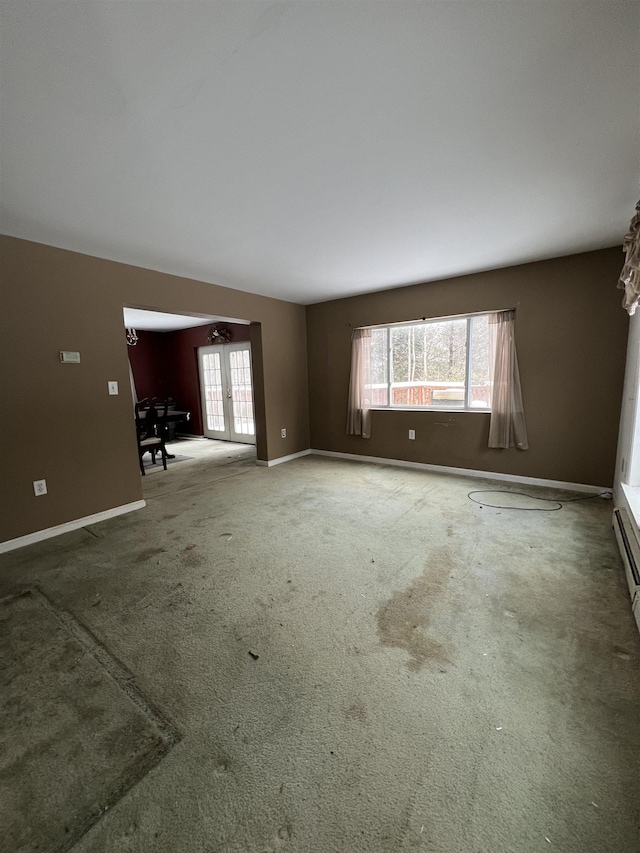 unfurnished living room featuring carpet floors and french doors