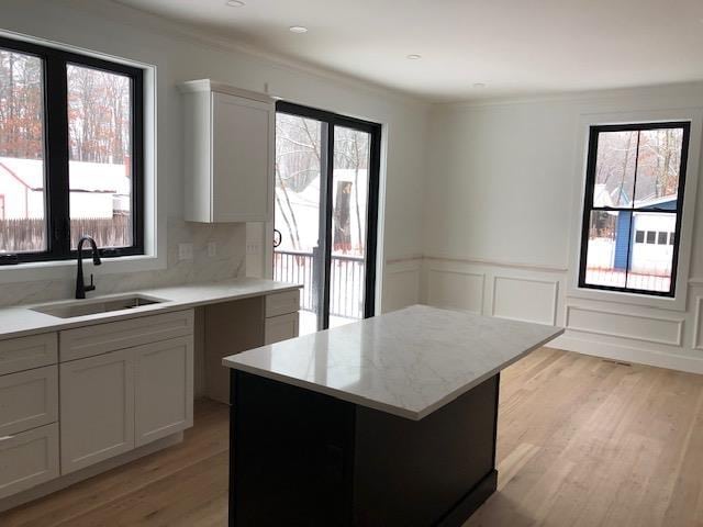 kitchen with white cabinets, sink, a kitchen island, and light hardwood / wood-style flooring