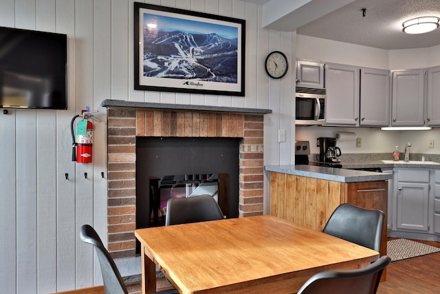 kitchen with gray cabinetry, sink, a fireplace, a textured ceiling, and wood-type flooring