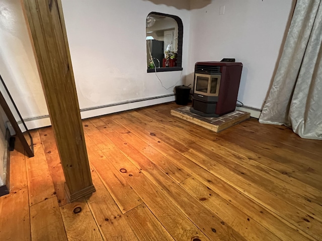 interior space with wood-type flooring, a baseboard heating unit, and a wood stove