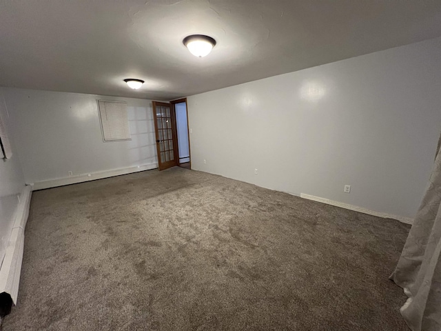 unfurnished room featuring dark colored carpet and a baseboard heating unit