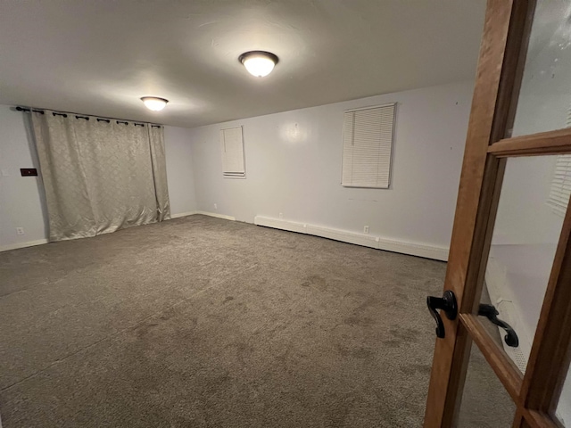 unfurnished room featuring a baseboard heating unit and dark carpet