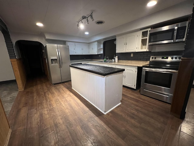 kitchen featuring appliances with stainless steel finishes, sink, white cabinets, dark hardwood / wood-style flooring, and a center island