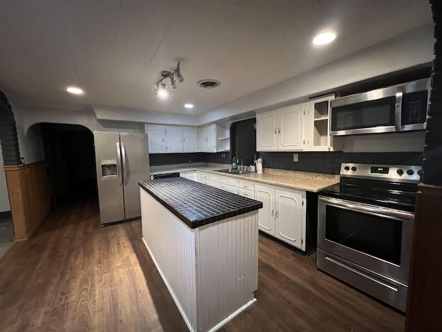 kitchen with dark wood-type flooring, stainless steel appliances, a center island, and white cabinets