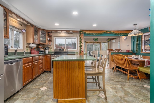 kitchen with hanging light fixtures, stainless steel appliances, a breakfast bar, a kitchen island, and sink