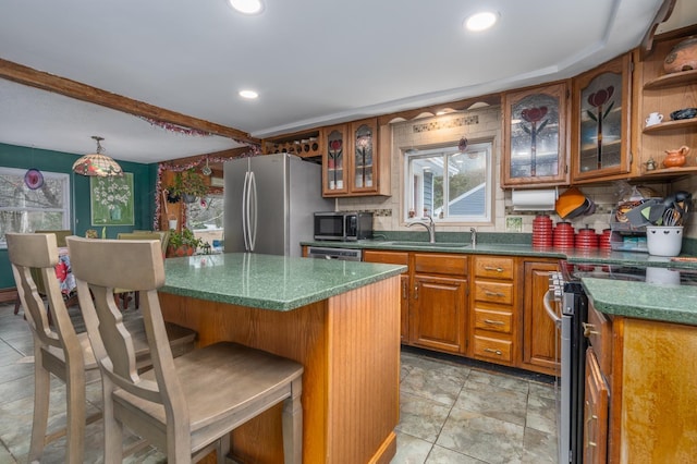 kitchen with stainless steel appliances, sink, a center island, beamed ceiling, and a breakfast bar