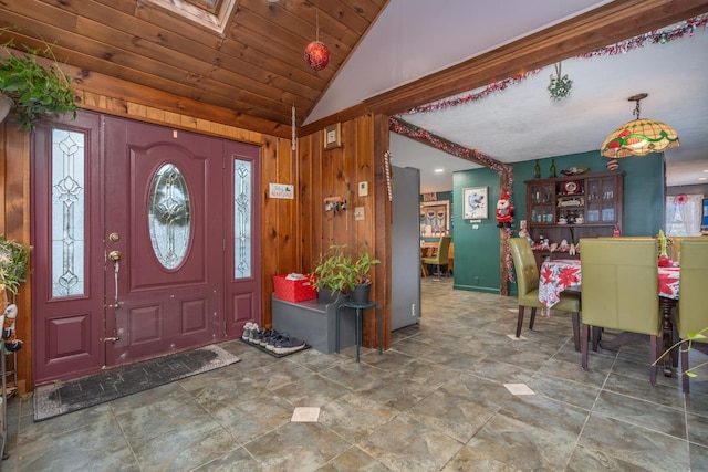 foyer entrance featuring lofted ceiling with skylight, wooden walls, and wooden ceiling