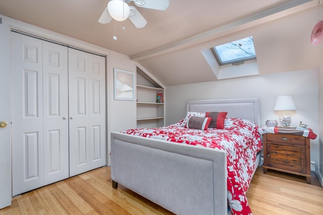 bedroom with wood-type flooring, ceiling fan, vaulted ceiling with skylight, and a closet