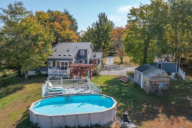 view of pool with a lawn, a pergola, a wooden deck, and an outdoor structure