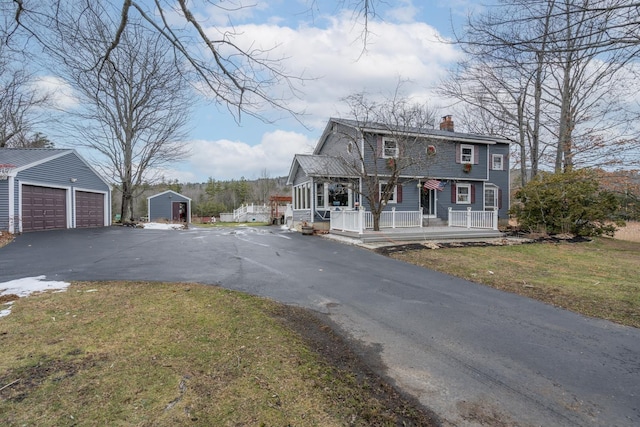 view of front facade with a front yard, a garage, a porch, and a shed