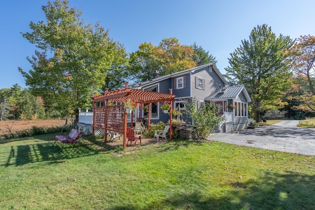 exterior space featuring a sunroom, a front lawn, and a pergola