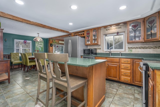 kitchen featuring stainless steel appliances, a kitchen bar, decorative backsplash, a wealth of natural light, and hanging light fixtures