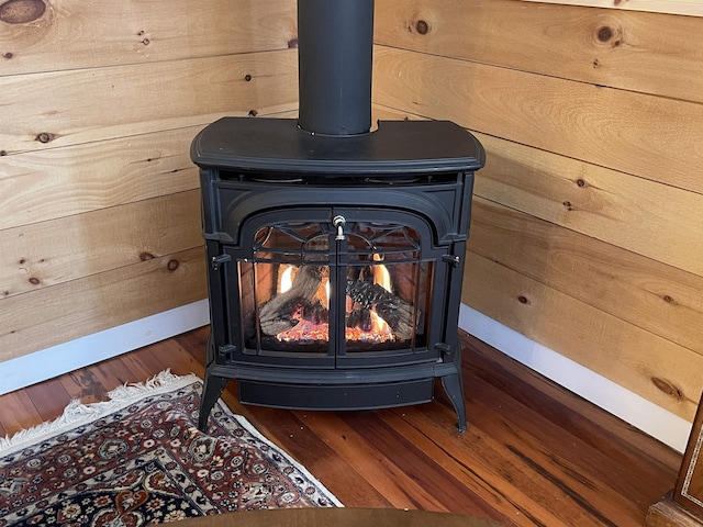 interior details featuring hardwood / wood-style floors, wood walls, and a wood stove