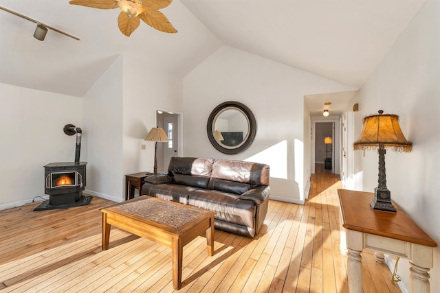 living room with ceiling fan, light wood-type flooring, high vaulted ceiling, and a wood stove