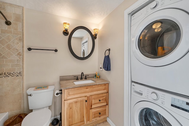 bathroom with a textured ceiling, vanity, toilet, and stacked washer / dryer