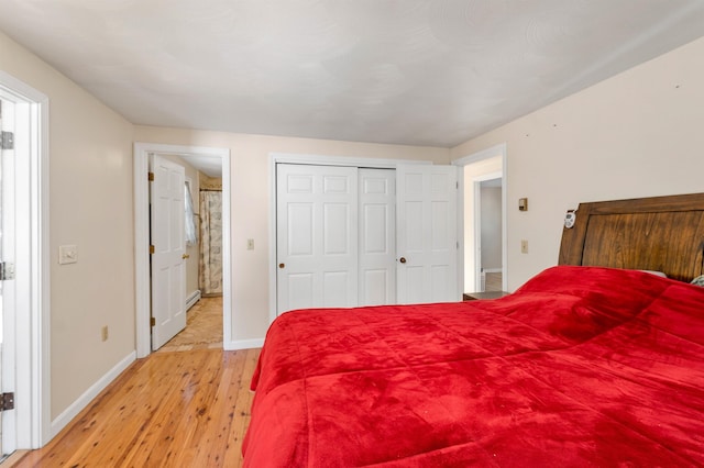 bedroom with a closet, a baseboard radiator, and light hardwood / wood-style flooring