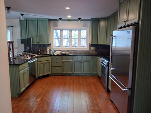 kitchen with sink, stainless steel appliances, tasteful backsplash, green cabinets, and light wood-type flooring