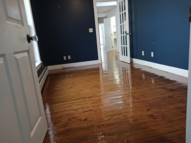 unfurnished room with hardwood / wood-style flooring and a baseboard radiator