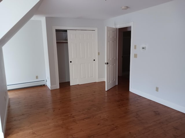 unfurnished bedroom with baseboard heating and dark wood-type flooring