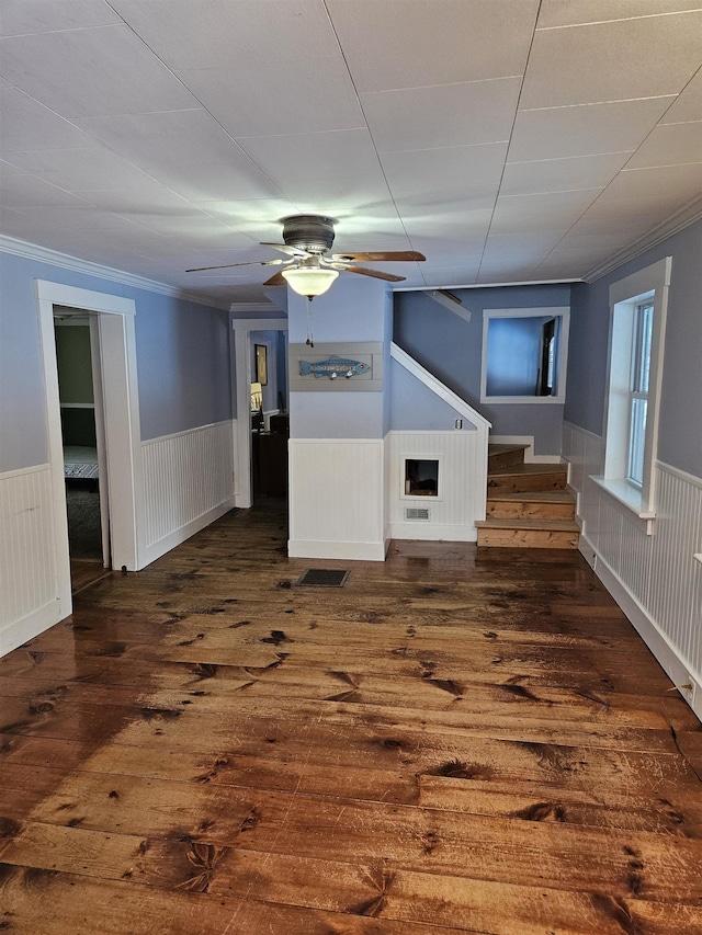 interior space with a fireplace, dark hardwood / wood-style flooring, ceiling fan, and ornamental molding