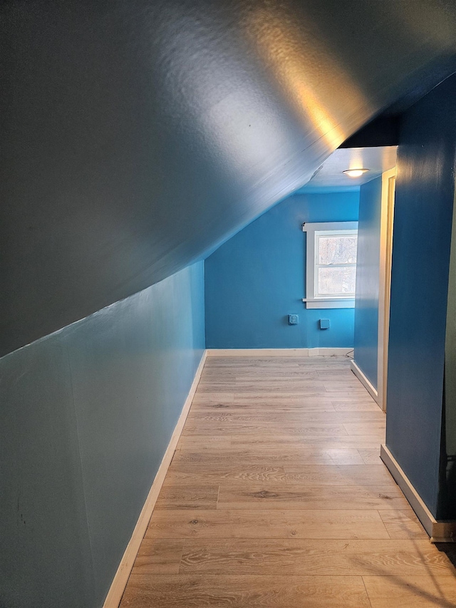 bonus room with light wood-type flooring and vaulted ceiling