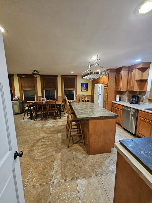 kitchen featuring a breakfast bar, pendant lighting, white refrigerator, dishwasher, and a kitchen island