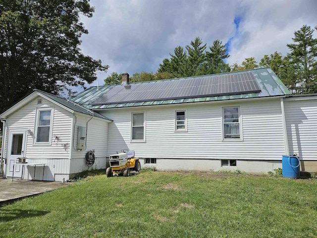 rear view of house featuring a patio area, a yard, and solar panels