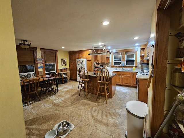 kitchen with a kitchen breakfast bar, stove, sink, white fridge, and a kitchen island