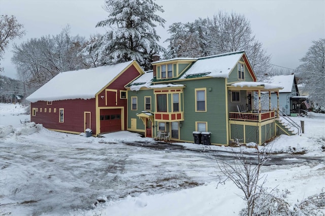 snow covered back of property with a garage