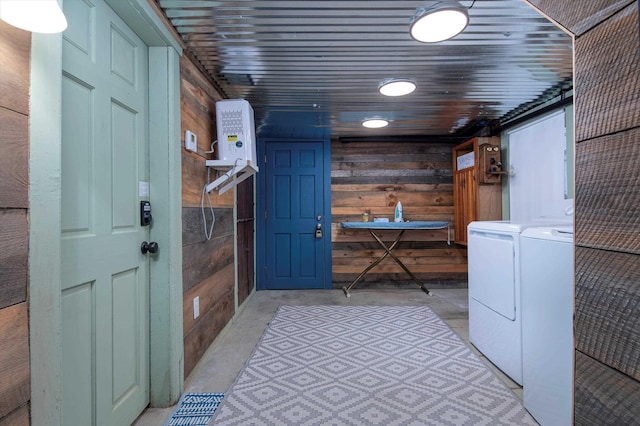 clothes washing area featuring separate washer and dryer and wooden walls