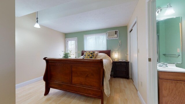 bedroom featuring an AC wall unit, sink, and light hardwood / wood-style flooring