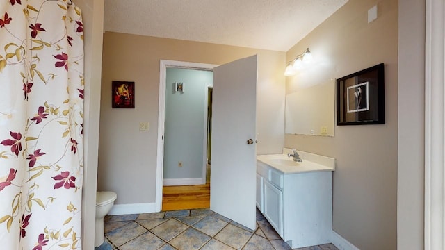 bathroom with tile patterned floors, vanity, a textured ceiling, and toilet