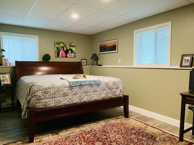 bedroom featuring a drop ceiling and wood-type flooring