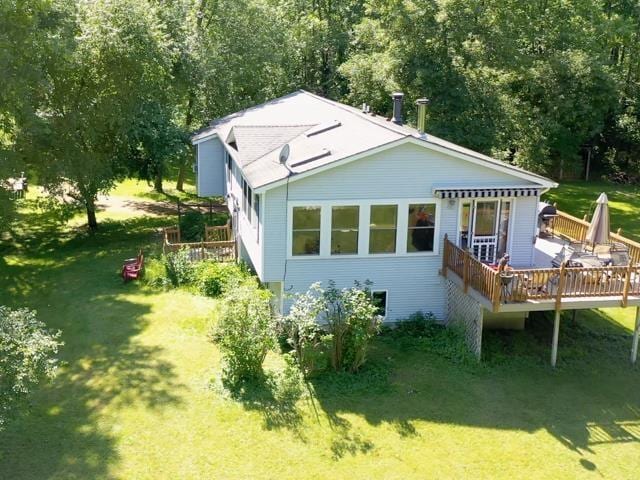 rear view of property featuring a lawn and a deck