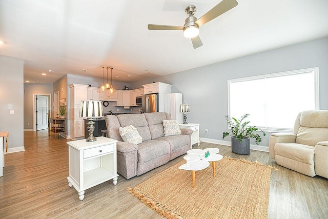 living room with ceiling fan and light hardwood / wood-style flooring