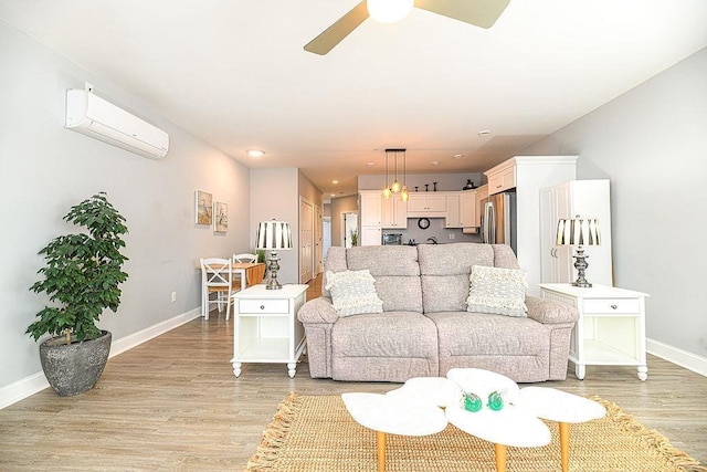 living room featuring ceiling fan, light hardwood / wood-style floors, and a wall unit AC